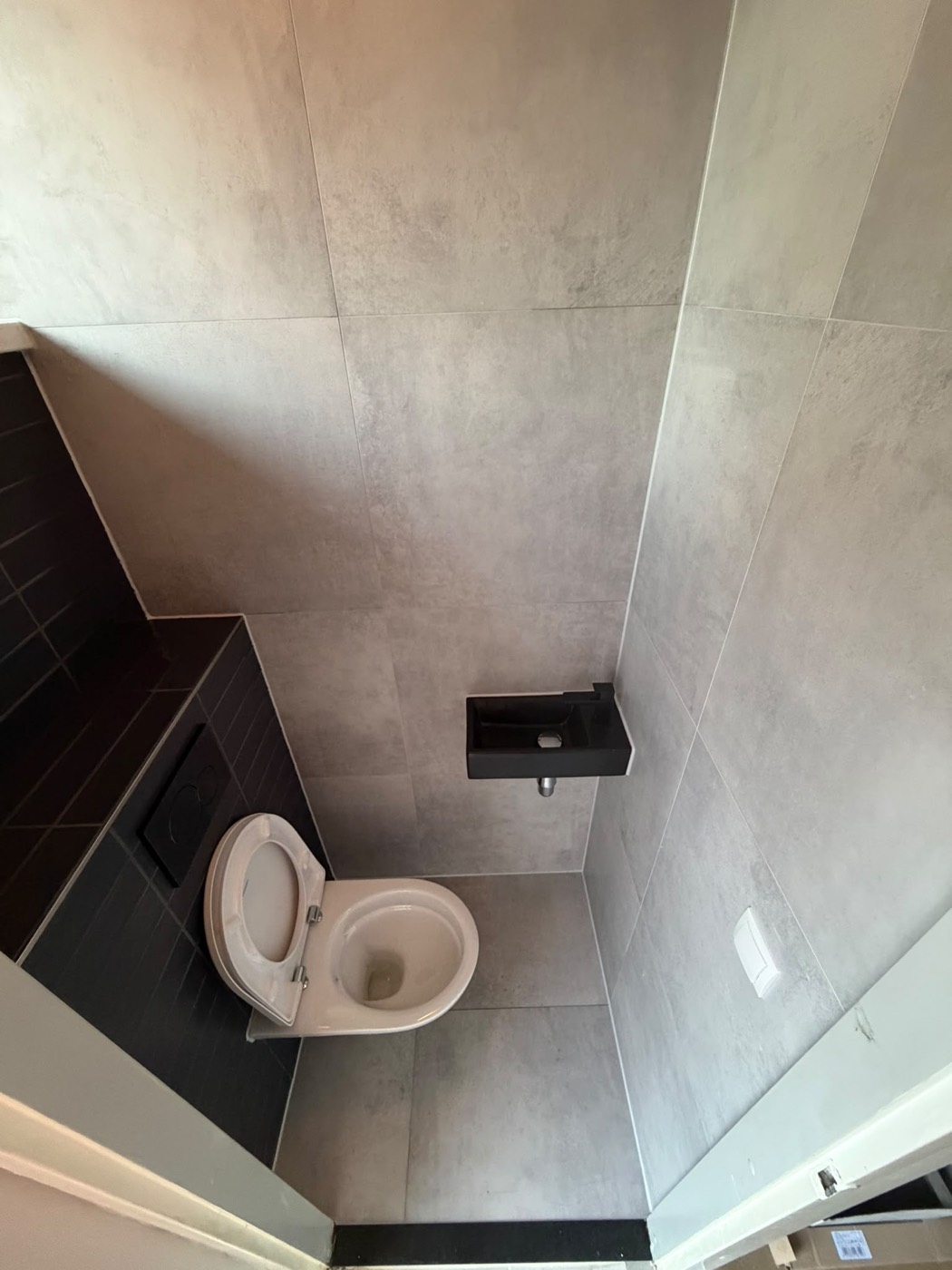 Toilet renovatie Alphen aan den Rijn van bovenaf, grijze vloertegels en zwarte accentwand