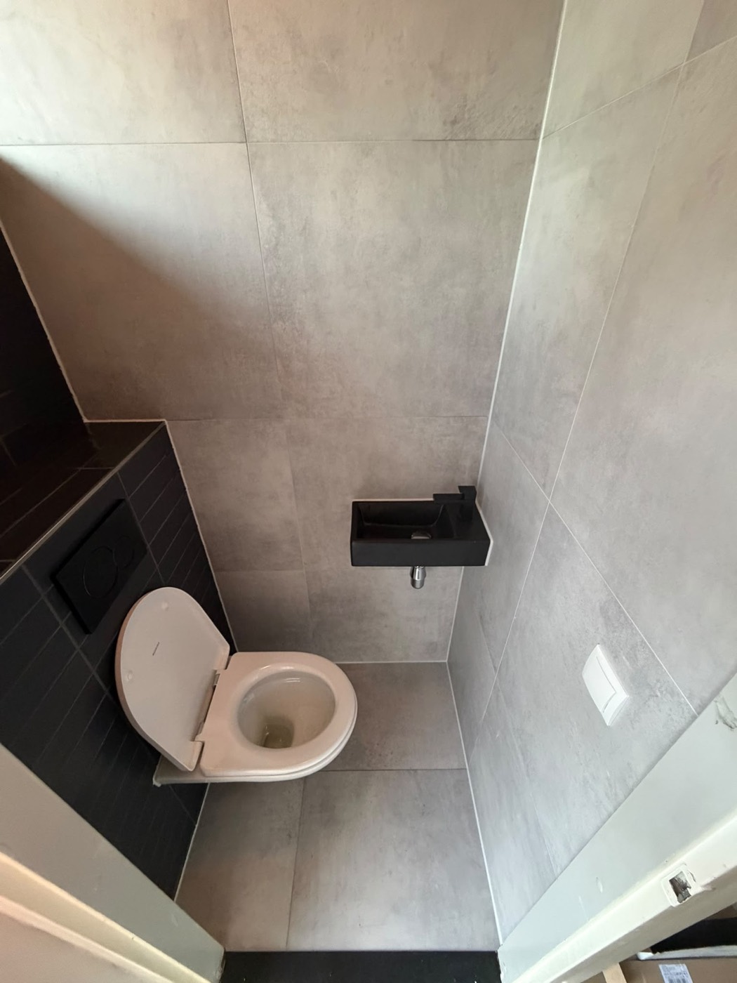 Strak toilet in Alphen aan den Rijn met grijze betonlook tegels en zwarte wastafel