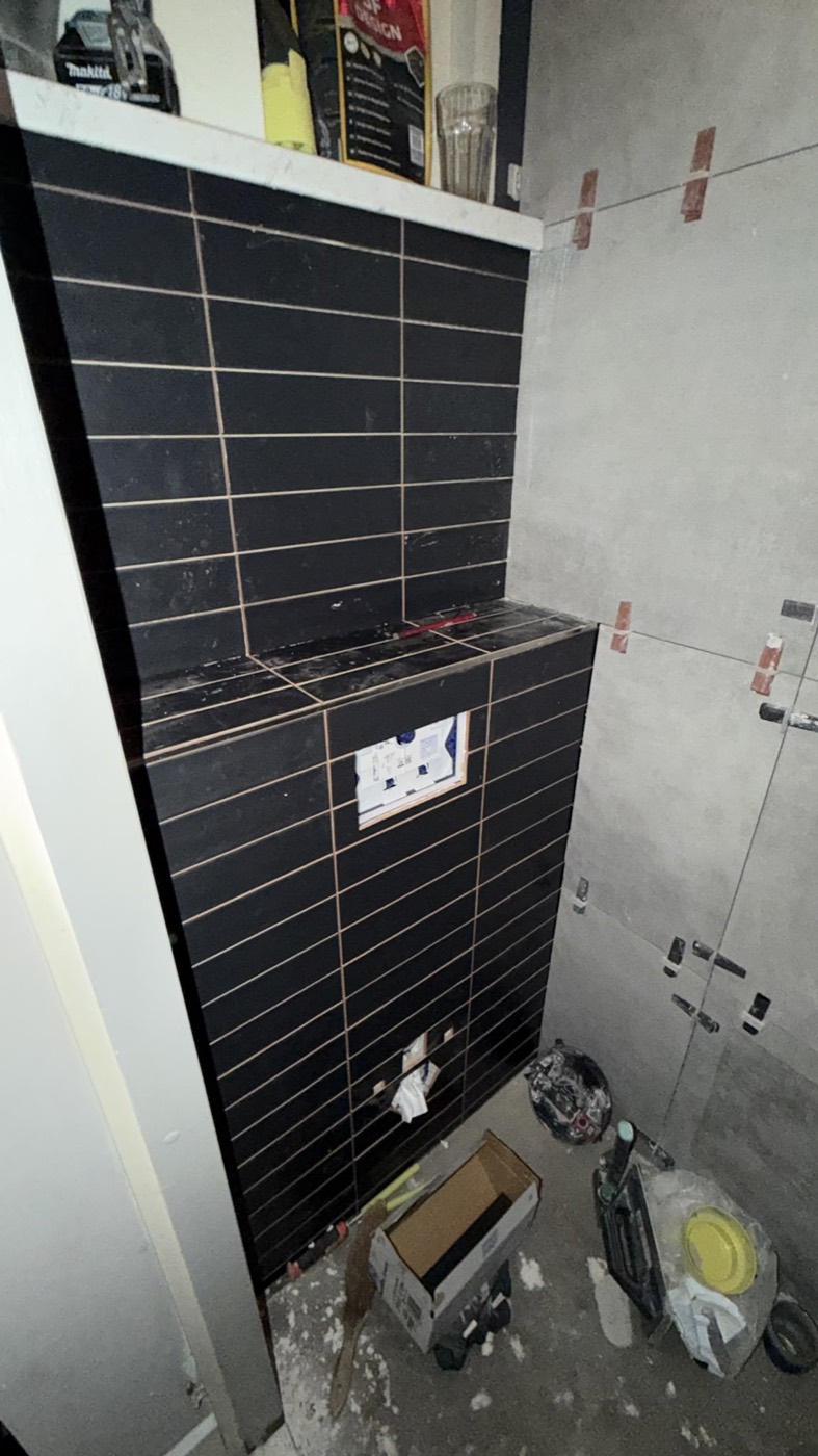 Zwarte tegels zetten achter het toilet, toilet renovatie in het Groene Hart door Groene Hart Badkamers