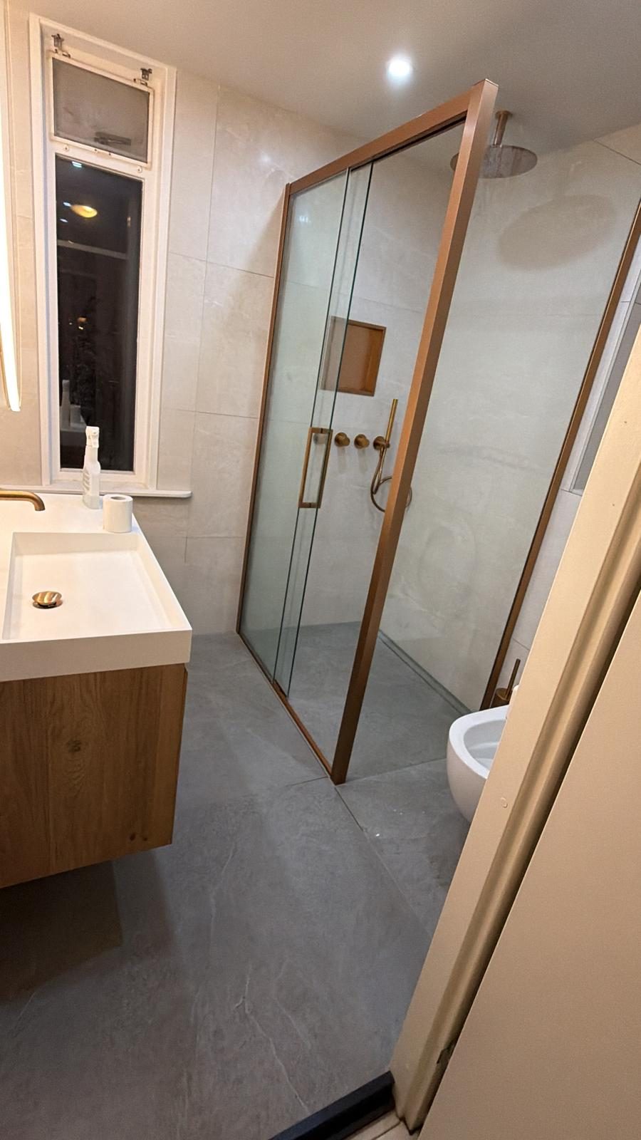 Opgeleverde badkamer met bronzen douche en eiken meubel