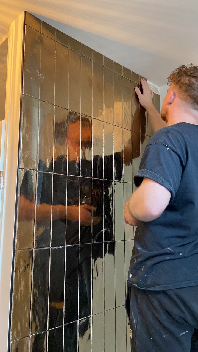 Donkere glanzende staande tegels worden strak geplaatst